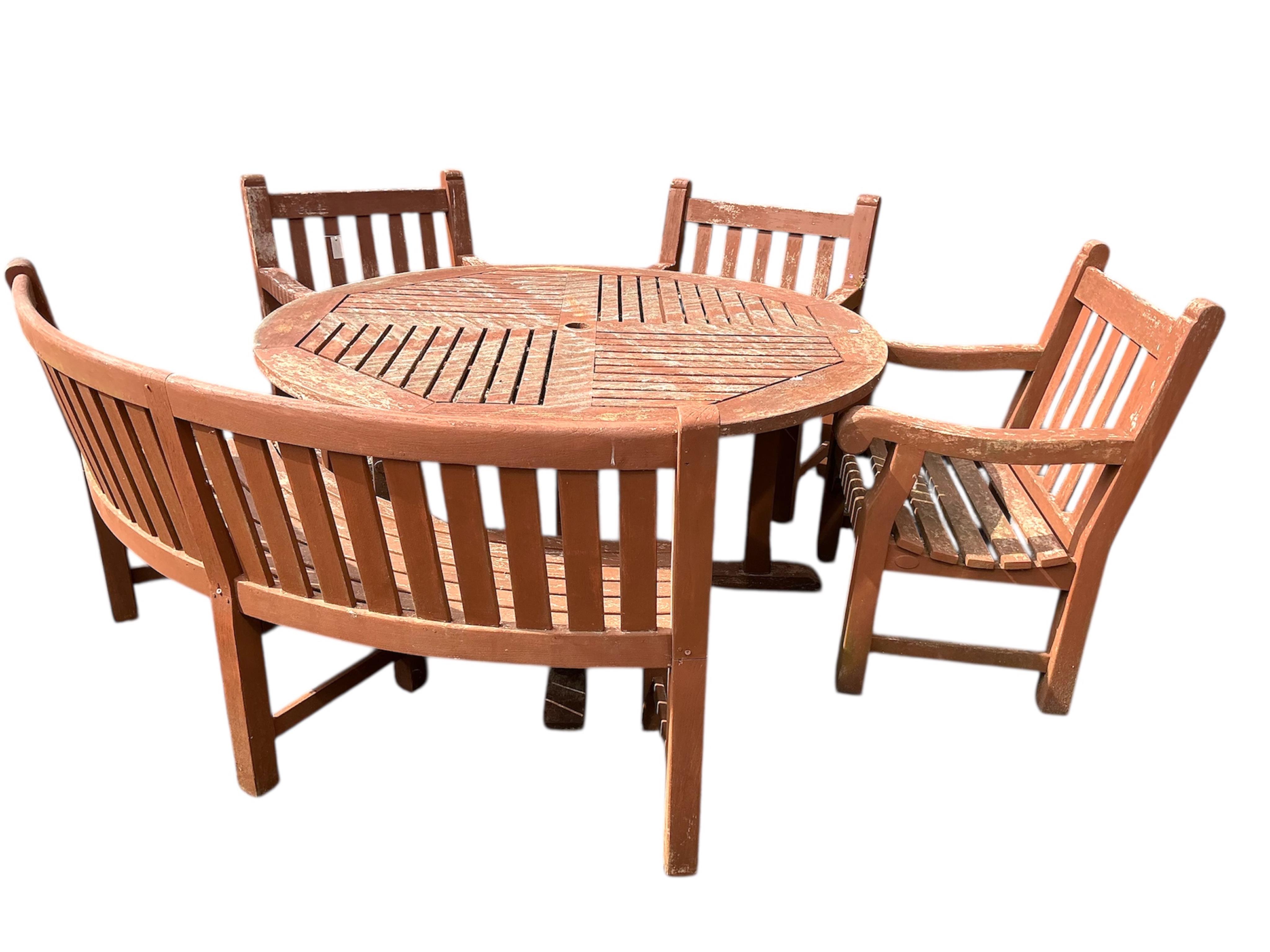 A circular stained teak garden table, diameter 151cm, height 73cm, three armchairs and a curved bench
